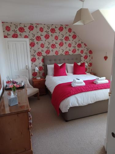 a bedroom with a large bed with red pillows at Strome Lodge in Inverness
