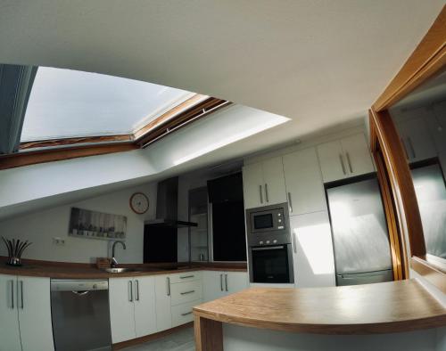 a kitchen with white cabinets and a skylight at Ático os porches in Allariz