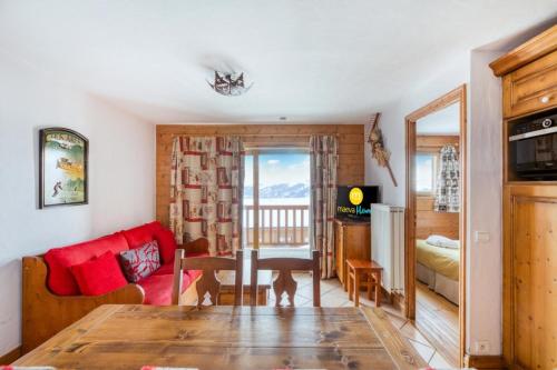 un salon avec une table et un canapé rouge dans l'établissement Résidence Les Alpages de Chantel - maeva Home - Appartement 3 Pièces 6 Personnes - Sélection MAE-6441, à Bourg-Saint-Maurice