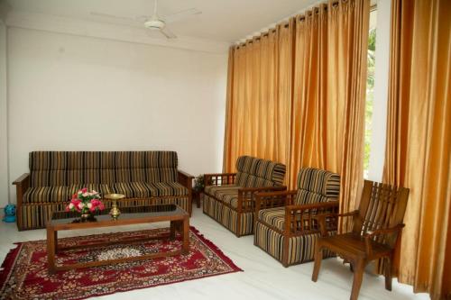 een woonkamer met een bank en 2 stoelen bij Ovenmin Villa in Haburugala