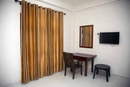 een kamer met een bureau, een stoel en een televisie bij Ovenmin Villa in Haburugala