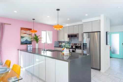 uma cozinha com paredes cor-de-rosa e uma grande ilha de cozinha em Caliente Oasis - A Ryson Property em Palm Springs