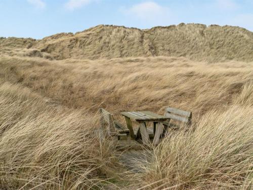 un banco de madera sentado en un campo de hierba alta en Holiday Home Emelia - 50m from the sea in NW Jutland by Interhome, en Torsted