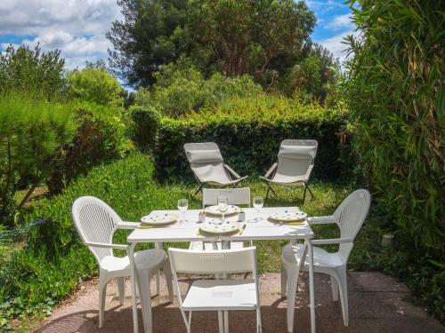 a white table and chairs in a garden at Apartment Jardins de la mer-10 by Interhome in Saint-Cyr-sur-Mer