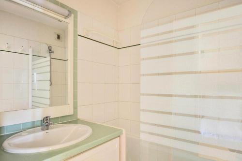 uma casa de banho branca com um lavatório e um espelho em Résidence Le Montana - maeva Home - Appartement 2 pièces 6 personnes - Conf 63 em La Mongie