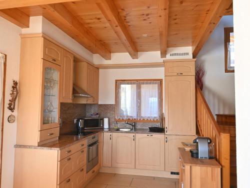 a kitchen with white cabinets and a wooden ceiling at Chalet Orchidée by Interhome in Ovronnaz