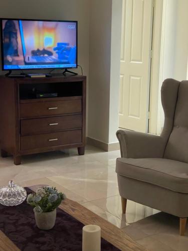 a living room with a tv and a chair and a table at A Luxury 2 Bedroom With a perfect location in Sweifiyeh in Amman