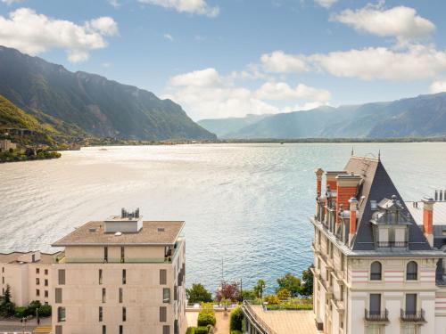 a view of a body of water with buildings and mountains at Apartment Les Terrasses C1-7 by Interhome in Montreux