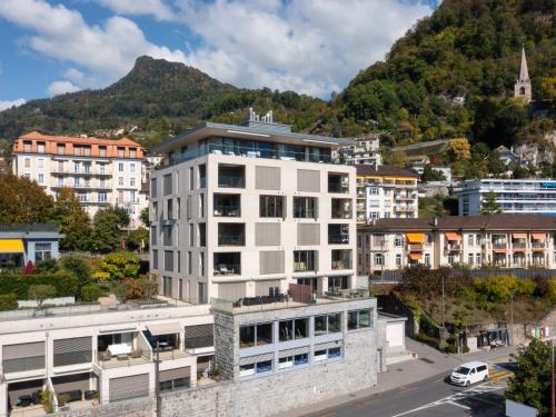 a white building in a city with a mountain at Apartment Les Terrasses C1-7 by Interhome in Montreux