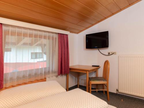 a bedroom with a desk and a tv on the wall at Apartment Aurora Apartment Top I by Interhome in Kappl
