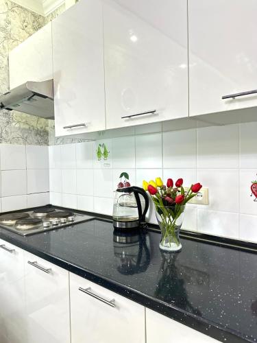 a kitchen with white cabinets and a vase of flowers at ЖК Тыныштык in Aktau