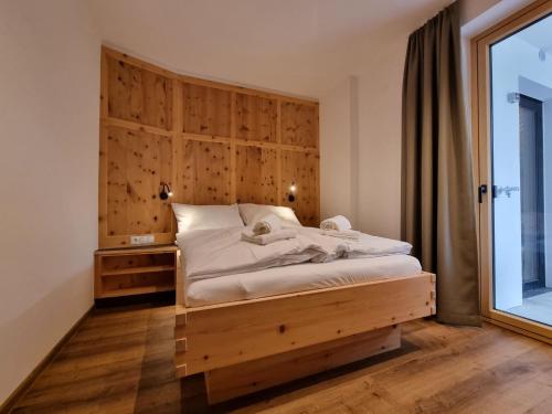 Schlafzimmer mit einem Bett mit einem Kopfteil aus Holz und einem Fenster in der Unterkunft Apartment Home Dachsbau by Interhome in See