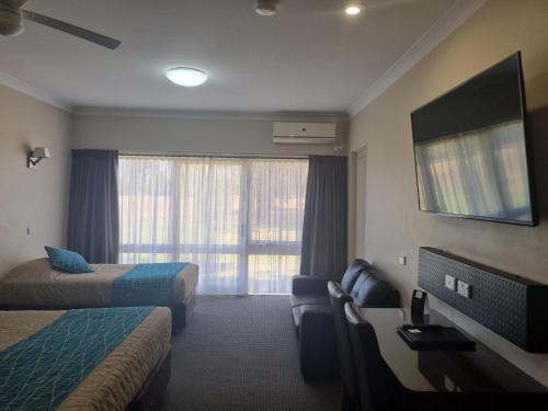 a hotel room with two beds and a flat screen tv at Australian Homestead Motor Lodge in Wagga Wagga