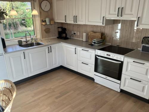a kitchen with white cabinets and a sink and a stove at Holiday Home Melvin - 700m from the sea in Funen by Interhome in Humble