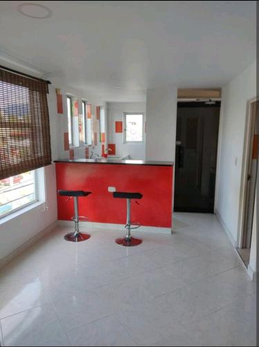 een keuken met een rode bar en 2 krukken bij Apartaestudio en arriendo in Neiva