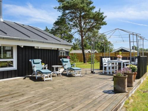 Holiday Home Santeri - 180m from the sea in NE Jutland by Interhome في Strandby: سطح خشبي مع كراسي وطاولة