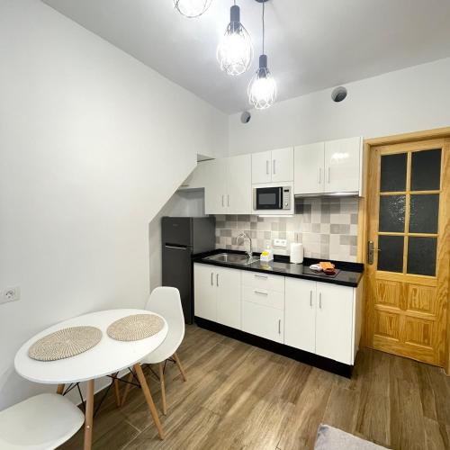 Una cocina con gabinetes blancos y una mesa y sillas. en Bajo Izquierda el Wiro, en Puerto