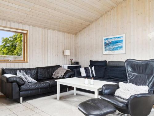sala de estar con sofá de cuero negro y mesa en Holiday Home Dagna - 400m from the sea in Lolland- Falster and Mon by Interhome en Rødby