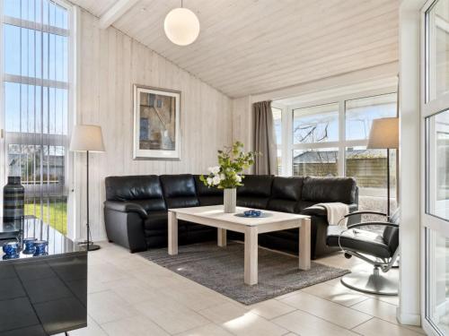 een woonkamer met een zwarte bank en een tafel bij Holiday Home Beske - 130m from the sea in SE Jutland by Interhome in Odder