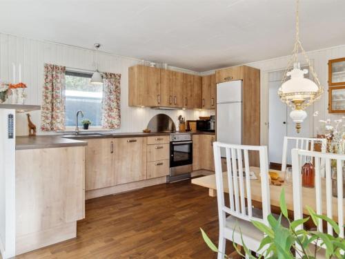 uma cozinha com armários de madeira e uma mesa e cadeiras em Holiday Home Oona - 1-8km from the sea in Sealand by Interhome em Vig