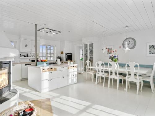 cocina con armarios blancos, mesa y sillas en Holiday Home Jeppe - 200m from the sea in NW Jutland by Interhome, en Blokhus