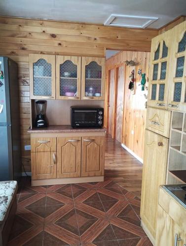 uma cozinha com armários de madeira e um micro-ondas em Cabañas quemchi em Quemchi