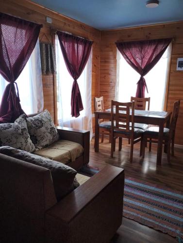 uma sala de estar com um sofá, uma mesa e janelas em Cabañas quemchi em Quemchi