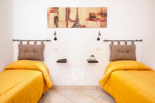 LIBERA HOUSE - Sweet Apartments في سان سالفو: سريرين في غرفة ذات أغطية صفراء