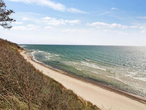 a sandy beach with the ocean in the background at Holiday Home Herlek - 450m from the sea in Bornholm by Interhome in Åkirkeby