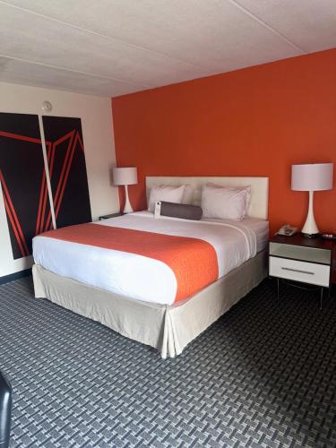 1 dormitorio con 1 cama grande y pared de color naranja en Howard Johnson by Wyndham Newburgh en Newburgh