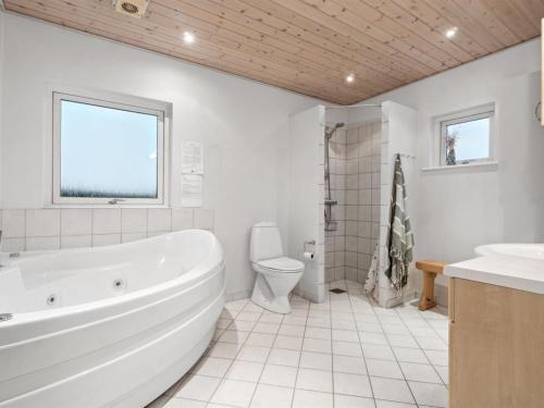 a white bathroom with a tub and a toilet at Holiday Home Ani - 600m from the sea in NW Jutland by Interhome in Torsted