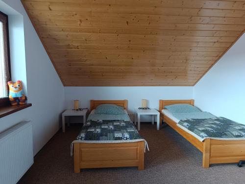 two beds in a room with a wooden ceiling at Tatry TOP Dom in Vavrišovo
