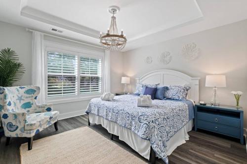 a bedroom with a bed and a chair and a chandelier at Luxury Getaway! Brand New 4BD! Near Coligny Beach in Hilton Head Island