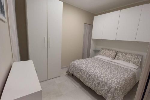 Dormitorio pequeño con cama y armarios blancos en Casa vacanza Al Cortiletto, en Sortino