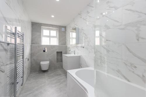 a white bathroom with a tub and a toilet at Spacious 1 bed apartment in centre of Walton Town in Walton-on-Thames