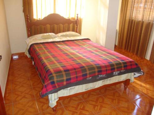 a bed with a plaid blanket on top of it at Villa hospedaje in Huaraz