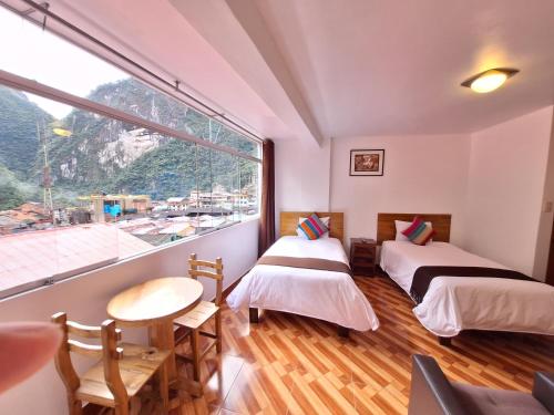 two beds in a room with a large window at Mapi Gardens Machupicchu B&B in Machu Picchu