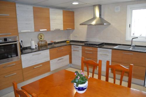 a kitchen with a wooden table with chairs and a sink at Casa Cal Tòfol in Font-Rubí