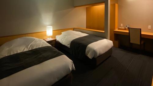 a hotel room with two beds and a table with a lamp at Minakamisansou in Minakami