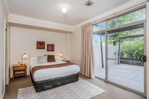 een slaapkamer met een bed en een glazen schuifdeur bij CityStyle Apartments in Canberra