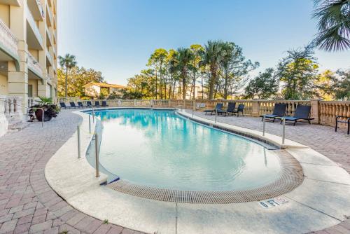 a swimming pool with chairs and trees in front of a building at Sailmakers Place 703 in Perdido Key