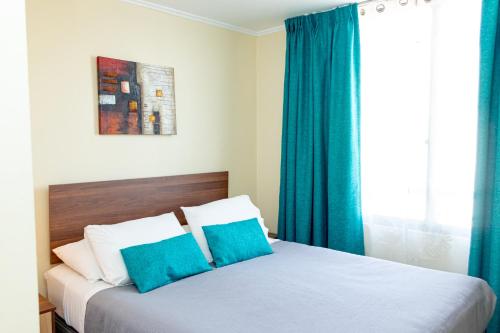 a bedroom with a bed with blue curtains and a window at Departamentos Amoblados Torre Tagle in Santiago