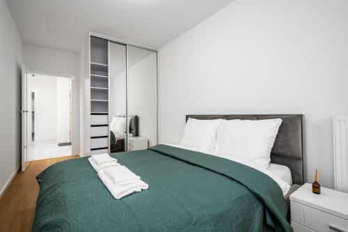 ein Schlafzimmer mit einem grünen Bett mit zwei Handtüchern darauf in der Unterkunft D&K Apart 1 Sierpnia 32A in Warschau