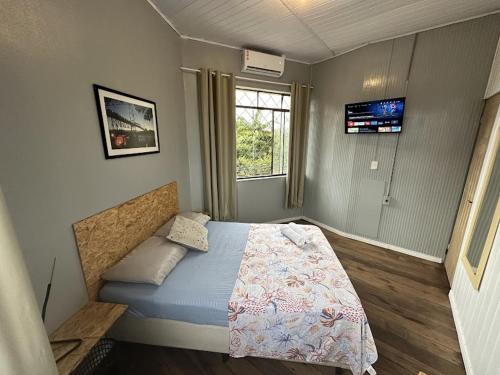 a bedroom with a bed and a tv on the wall at Quarto Econômico com Ar Cond. e Smart Tv Netflix in Itajaí