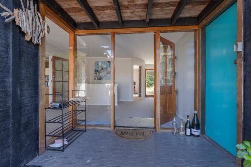 een kamer met een glazen deur en een kamer met wijnflessen bij Perfect Picture on Haddon in Whitianga