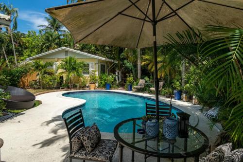 a pool with a table and an umbrella and chairs at Charming Cottage 1BR, Pool, Victoria Park in Fort Lauderdale