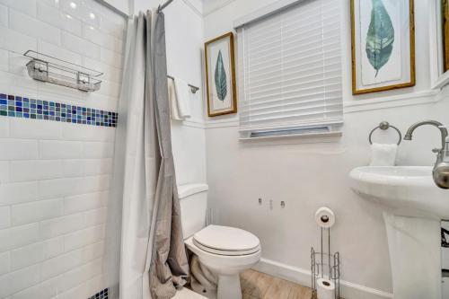 a white bathroom with a toilet and a sink at Charming Cottage 1BR, Pool, Victoria Park in Fort Lauderdale
