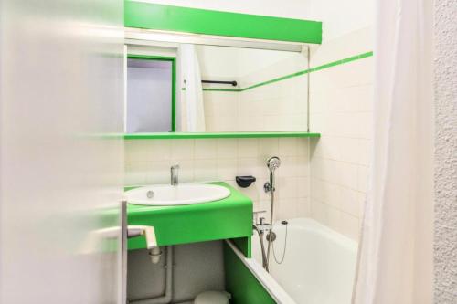 een badkamer met een groene wastafel en een bad bij Résidence Le Cédrat - maeva Home - Appartement 2 pièces 4 personnes avec 254 in Avoriaz