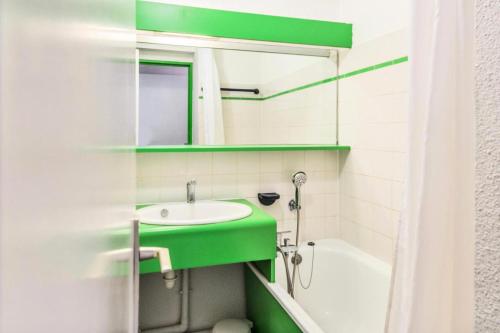 La salle de bains est pourvue d'un lavabo vert et d'une baignoire. dans l'établissement Résidence Le Cédrat - maeva Home - Appartement 2 pièces 4 personnes avec vue montagne - Sélection - Super Home MAE-9254, à Avoriaz