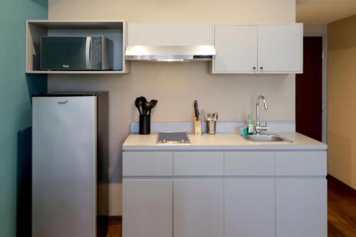 a kitchen with white cabinets and a sink and a microwave at City Express Suites by Marriott Tijuana Rio in Tijuana